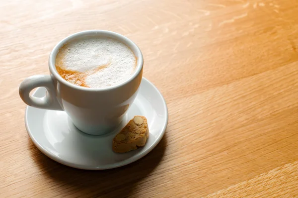 Cappuccino šálek na dřevěném stole — Stock fotografie