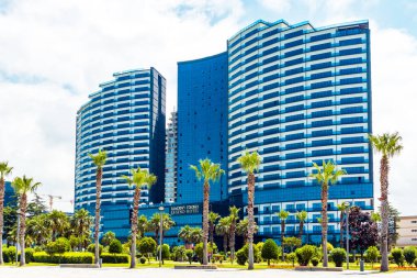 Palmiye ağaçları ve diğer ağaçlarla çevrili güzel yeni binalar.