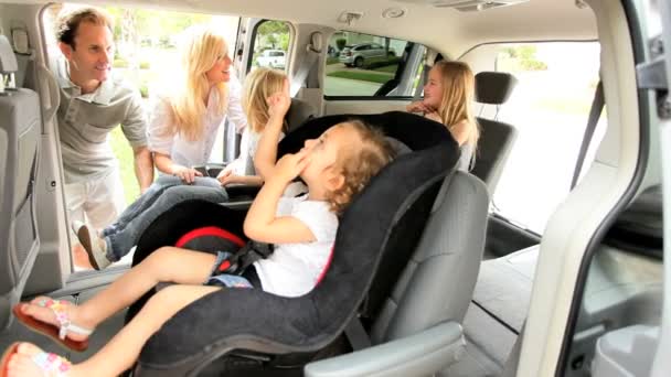 Padres poniendo asientos de coche familiares para niños — Vídeo de stock