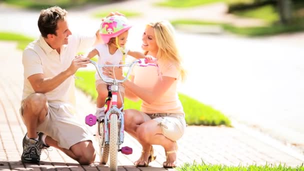 Padres jóvenes que apoyan a un niño pequeño en una bicicleta pequeña — Vídeo de stock