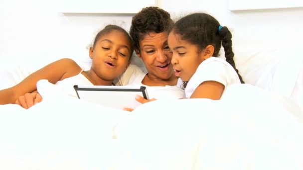 Africano americano mamá niñas cama inalámbrico tableta — Vídeo de stock