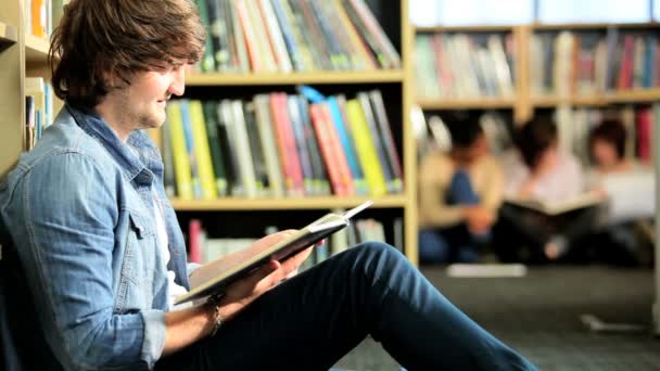 Estudiante joven estudiando libro de texto universitario — Vídeos de Stock