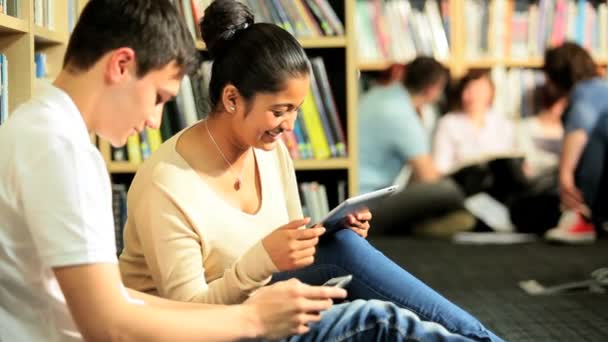 Diversos estudiantes investigando información de carrera en la biblioteca — Vídeo de stock