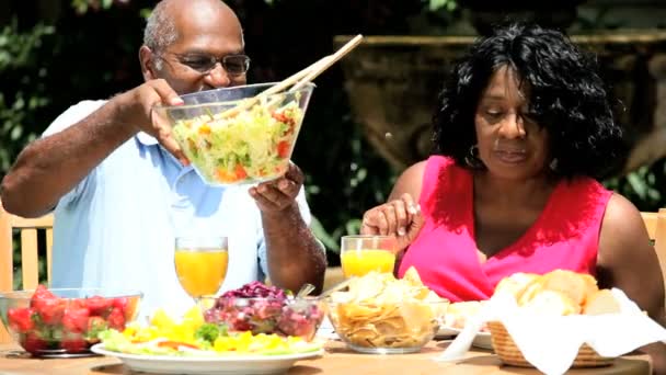 Pareja étnica comiendo ensalada en el jardín — Vídeo de stock
