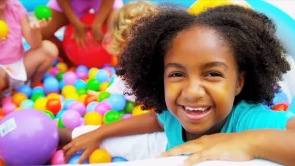 Смеющиеся многонациональные дети наслаждаются бассейном для игры в мяч — стоковое видео