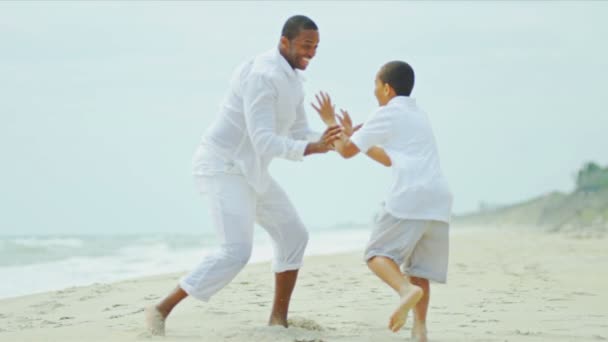 Разнообразные счастливые родители играют сына на пляже — стоковое видео