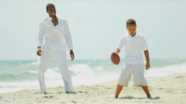 Son and father playing together American football by ocean — Stock Video