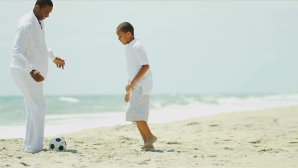 Juego de fútbol de hijo afroamericano y padre en la playa — Vídeo de stock