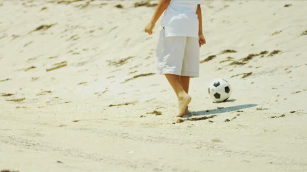 Diverse boy enjoying summer on beach playing with soccer ball — Stock Video