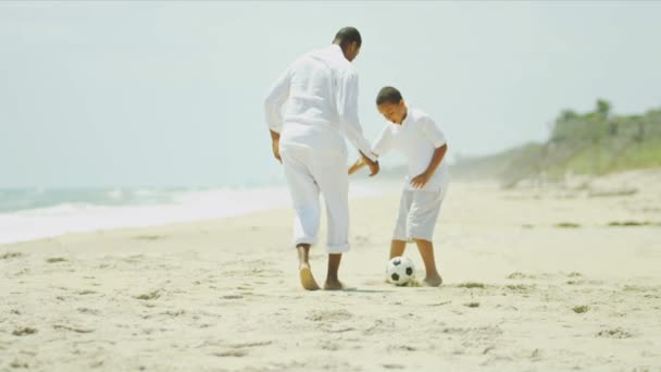Разнообразный отец учит сына играть в футбол на пляже — стоковое видео