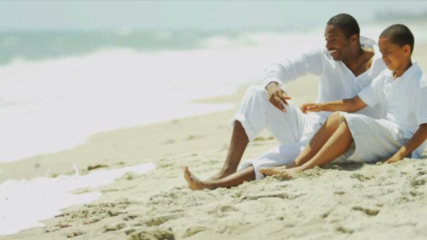 Etnik mutlu baba ile oğlu sahilde oturup eğlenceli — Stok video