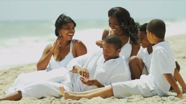 Padres étnicos hijos pasando tiempo juntos sentados en la playa — Vídeos de Stock