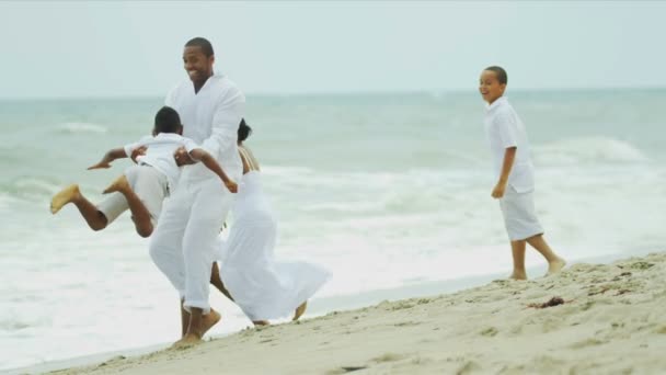 Famille ethnique éclaboussant et riant ensemble plage — Video