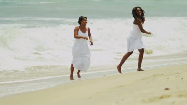 Ethnic mother playing and laughing with daughter on beach — Stock Video