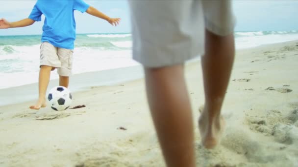 Hermanos étnicos pateando juntos fútbol en la playa — Vídeos de Stock