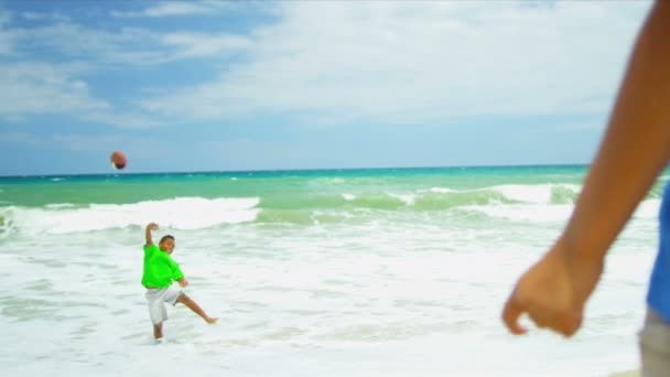 Dois irmãos étnicos desfrutando de jogo de futebol americano na praia — Vídeo de Stock