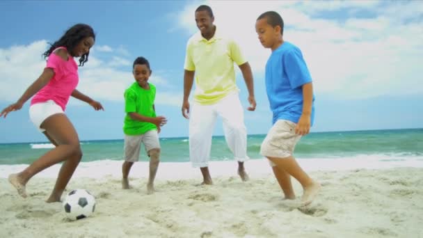 Juego de fútbol de padre étnico ingenio hijos pequeños e hija adolescente en la playa — Vídeo de stock