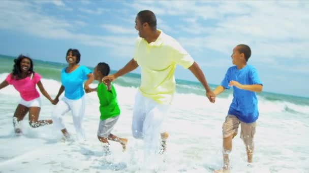 Genitori afroamericani bambini che si tengono per mano godendo correre in surf oceanici — Video Stock