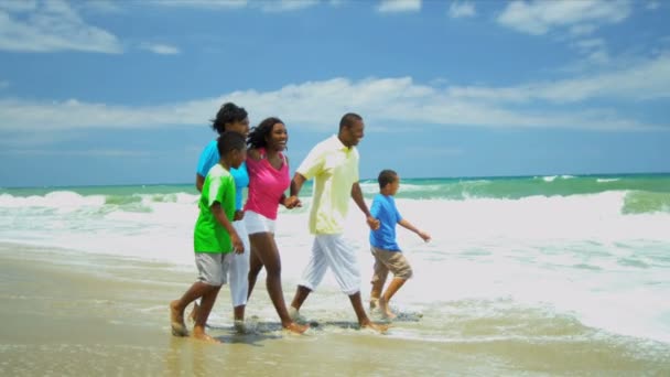 Ethnic parents children holding hands walking together in ocean surfs — Stock Video