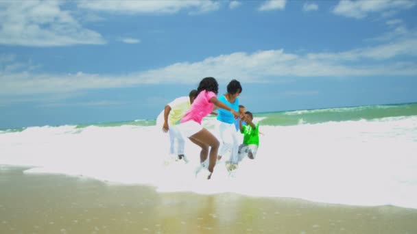 Ethnic parents holding hands children playing together in ocean surfs — Stock Video