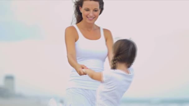 Caucasian girl enjoying time together mother dressed in white on beach