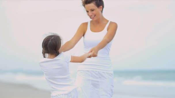 Caucasian girl enjoying beach dancing with mother