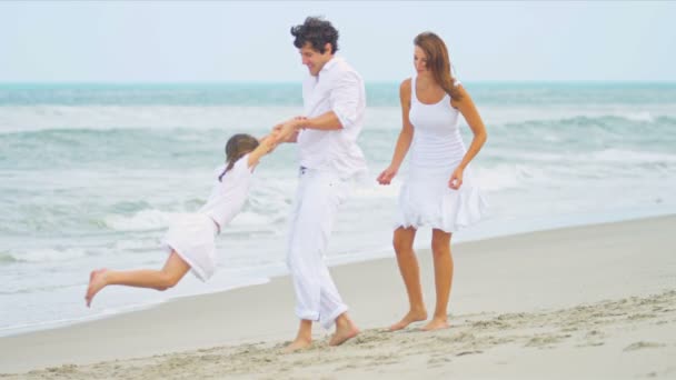 Menina caucasiana desfrutando de tempo juntos pais vestidos de branco na praia — Vídeo de Stock