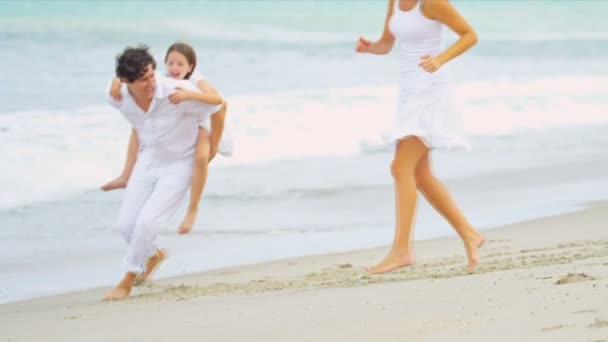 Καυκάσιος ευτυχείς γονείς διασκεδάζοντας μαζί η κόρη piggyback στην παραλία — Αρχείο Βίντεο