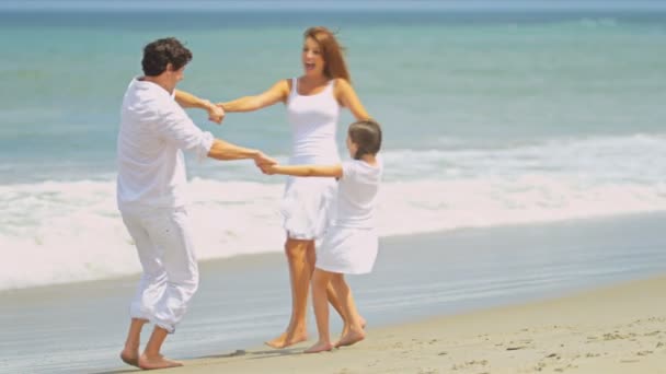 Joven familia caucásica disfrutando jugando en la playa juntos — Vídeos de Stock