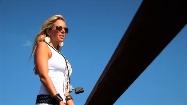 Elegant blonde woman standing on jetty and looking over the sea — Stock Video