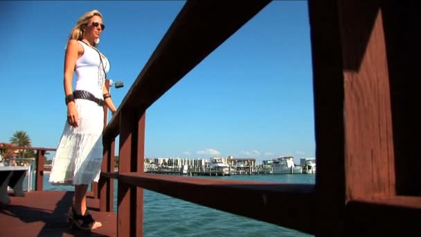 Elegante blonde vrouw permanent op steiger en kijkt uit over de zee — Stockvideo