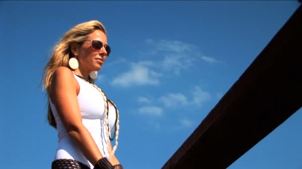 Elegante blonde vrouw permanent op steiger en kijkt uit over de zee — Stockvideo
