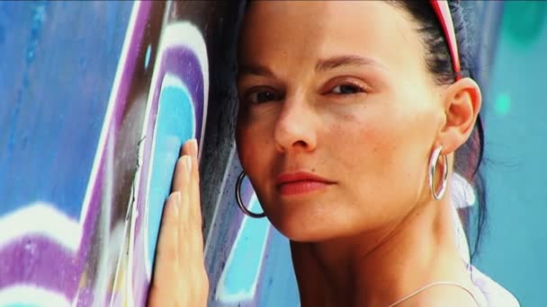 Beautiful fashion model posing to camera against grafitti wall — Stock Video