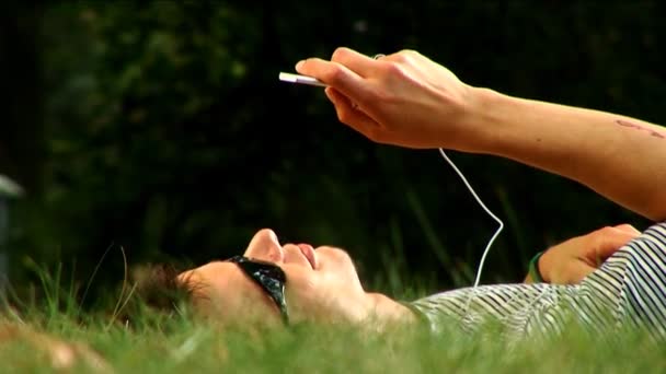 男青年躺在公园听音乐 — 图库视频影像