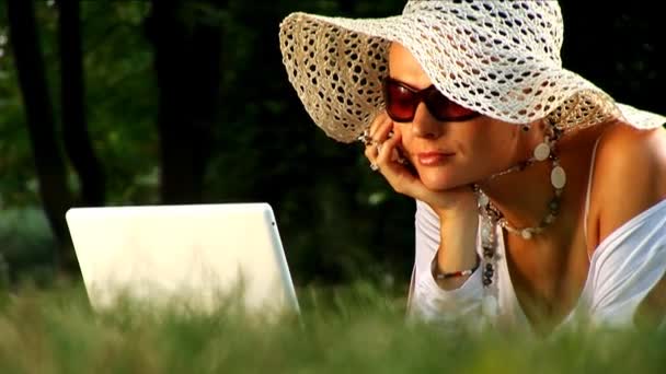 Ung kvinna ligga i parken med hjälp av bärbar dator — Stockvideo