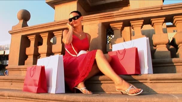 Hermosa mujer joven con bolsas de compras de diseño — Vídeos de Stock