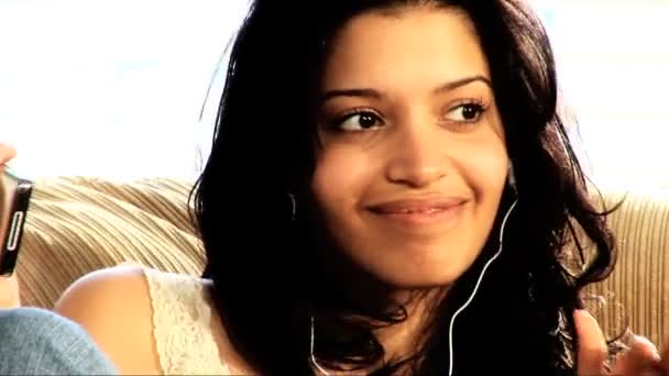 Hermosa chica latina en el sofá con su reproductor de MP3 — Vídeos de Stock