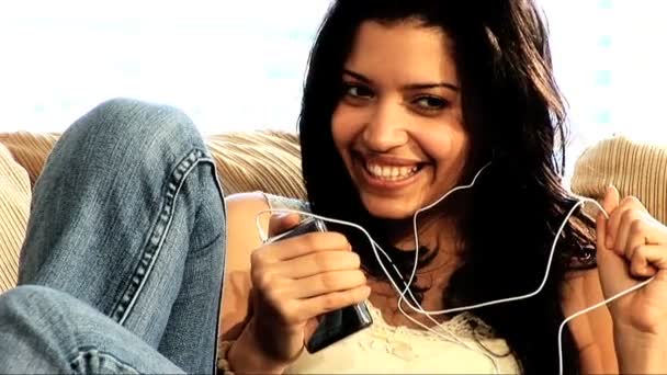 Menina latina bonita no sofá com seu leitor de MP3 — Vídeo de Stock