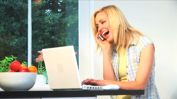 Beautiful young blonde girl using a laptop computer & mobile phone — Stock Video