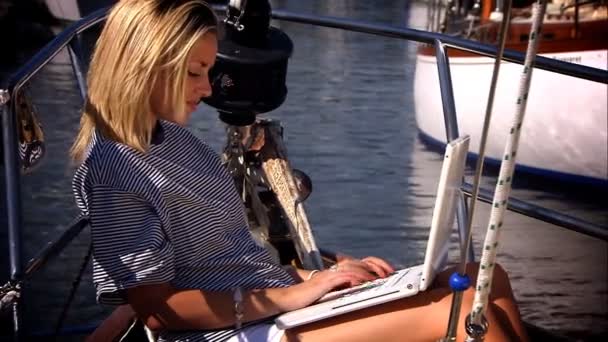 Schöne blonde Mädchen mit ihrem Laptop an Bord einer Luxusjacht — Stockvideo