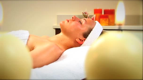 Beautiful blonde girl relaxing at health spa with candles burning — Stock Video