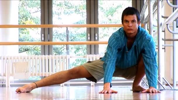 Houkutteleva nuori mies harjoittelee joogaa kuntosalilla — kuvapankkivideo
