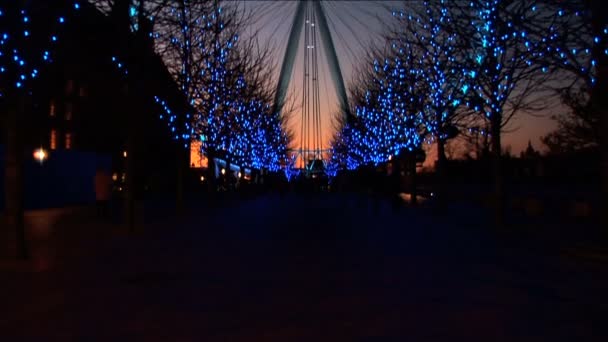 London Eye por la noche rodeado de decoraciones de luz navideñas — Vídeo de stock