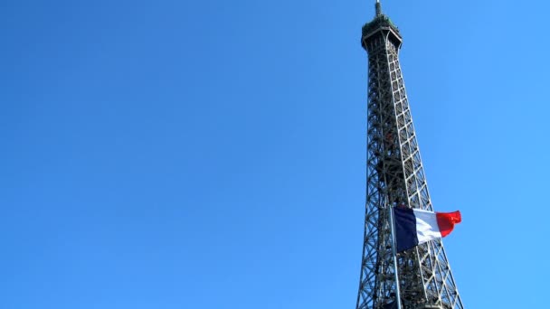 Torre Eiffel y bandera nacional francesa contra un cielo azul claro — Vídeo de stock
