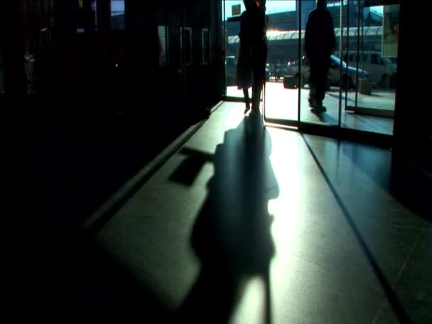 Commuters passing through the airport terminal in silhouette — Stock Video