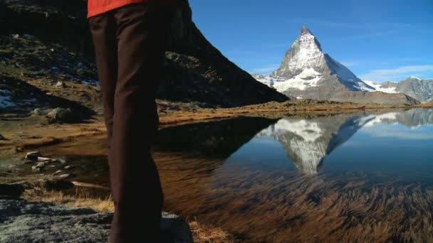 Female hiker in beautiful alpine landscape with lake & Matterhorn peak — Stock Video