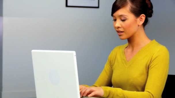 Young western oriental businesswoman using a laptop & mobile phone — Stock Video