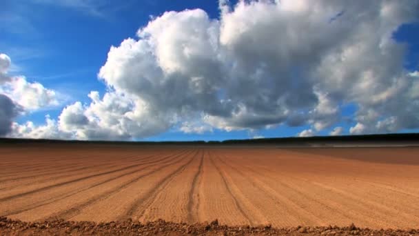 Dramatic time-lapse clouds over a ploughed field — Stock Video