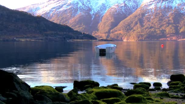 Маленькая лодка, плавающая в кристально чистой воде ледникового фьорда — стоковое видео