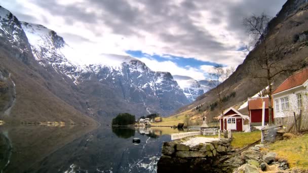 Time-lapse wolken boven externe huizen naast een glaciale fjord — Stockvideo